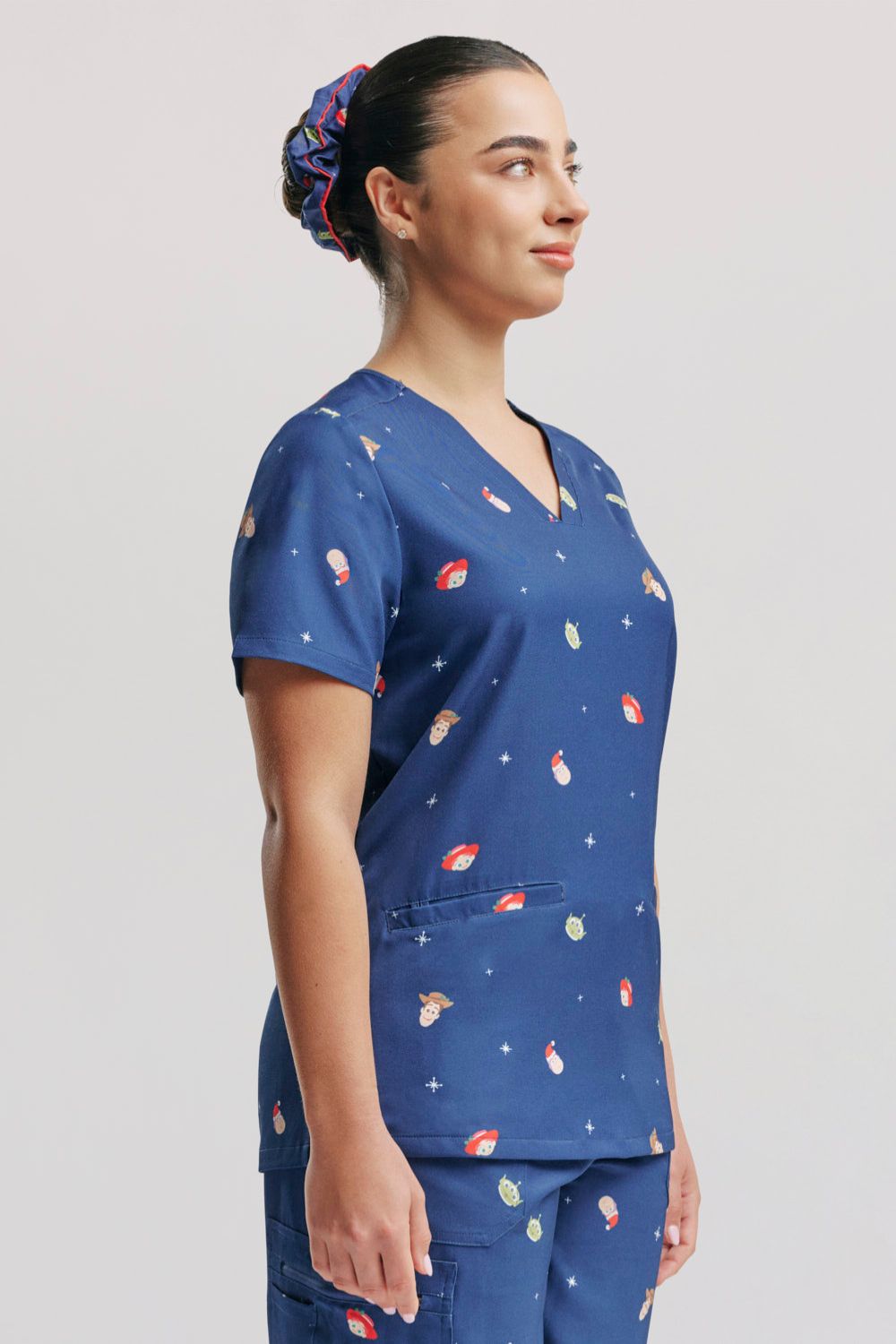 Side profile of a doctor wearing the dark blue Disney & Pixar Toy Story Christmas scrub top.  