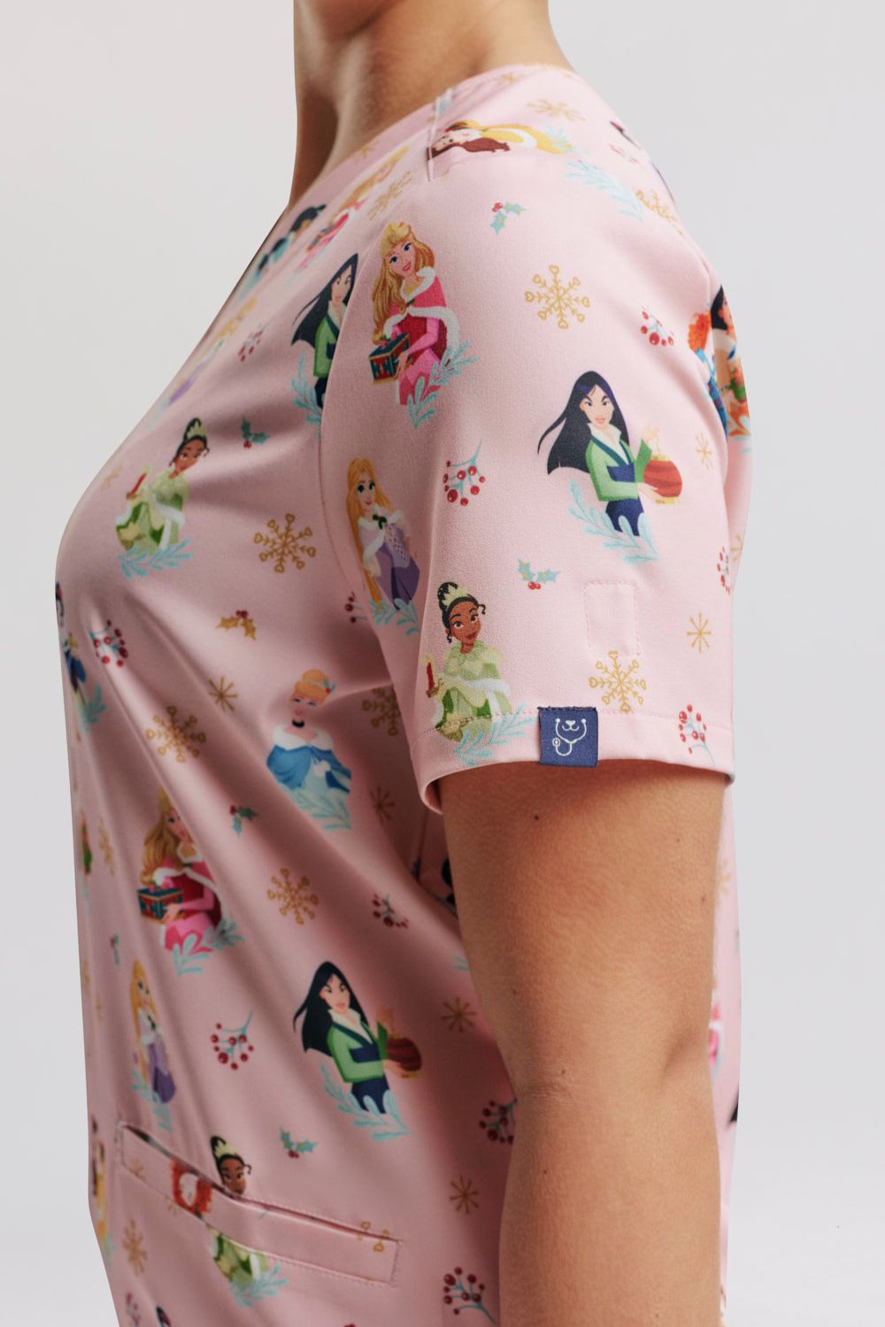Close-up studio shot focusing on the sleeve fit, side seam construction, and light pink holiday Disney Princess pattern layout.