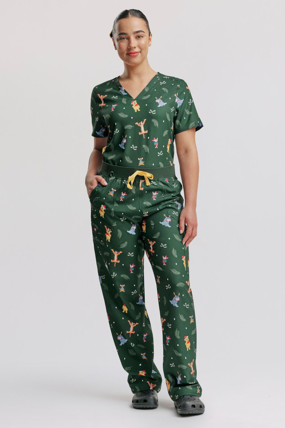 A doctor standing in the dark forest green Winnie the Pooh V-neck scrub top and matching cargo pants set.