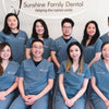 A team of dentists from Sunshine Family Dental wearing cool gray scrub uniforms