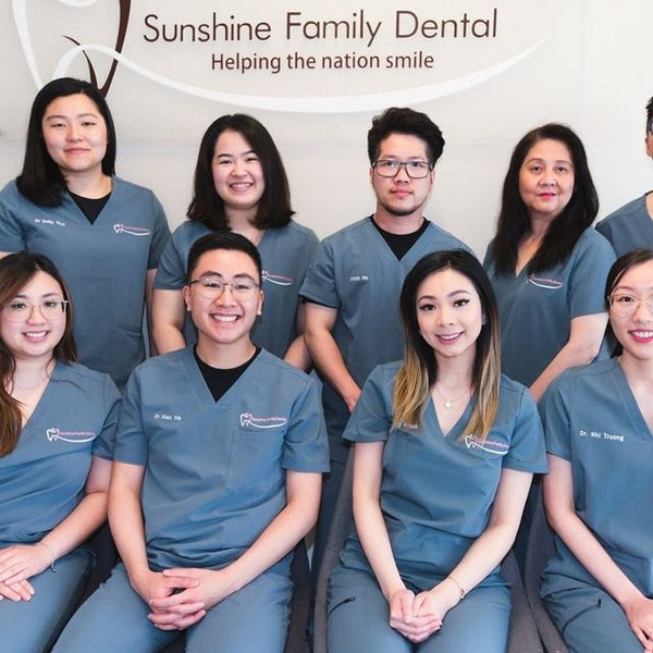 A team of dentists from Sunshine Family Dental wearing cool gray scrub uniforms