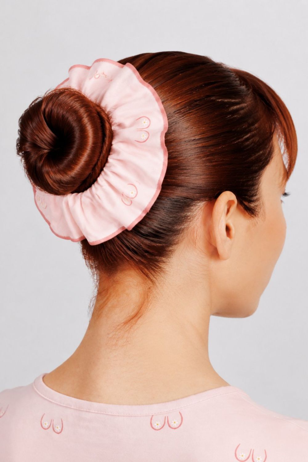 Close-up back view of a nurse with hair in a bun wearing a light pink scrunchie with line art small boobs print.