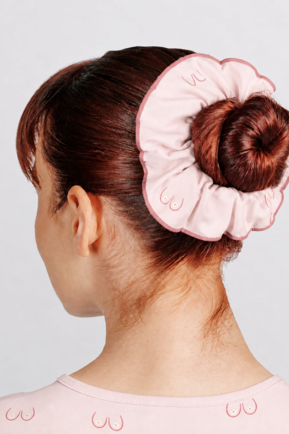 Back view of a vet nurse styled with a hair bun wearing a light pink scrunchie with line art small boobs print.