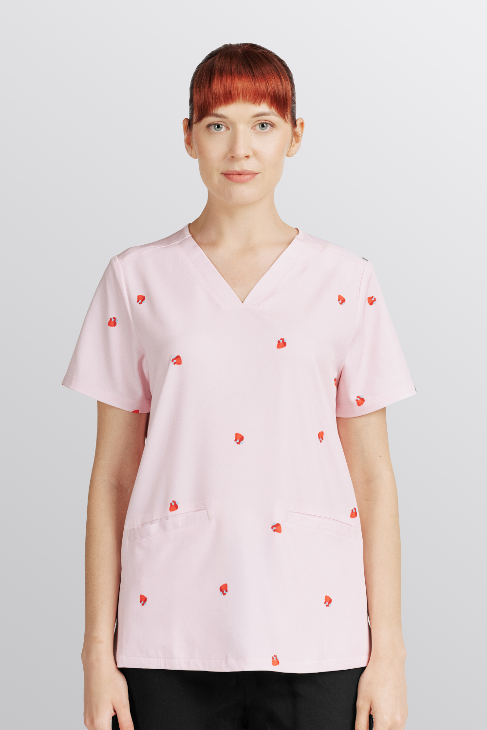  A Nurse wearing the Lub Dub Women's 3-Pocket Scrub top featuring light pink fabric with small red heart prints.