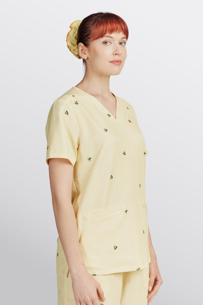 Three-quarter view of a dentist wearing a light yellow scrub top with mental health sunflower print.