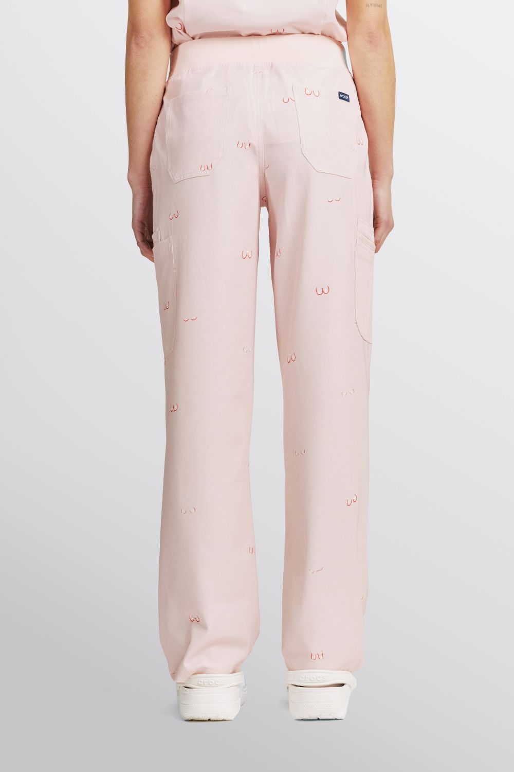 Back view of a veterinarian wearing light pink scrub pants with line art small boobs print.