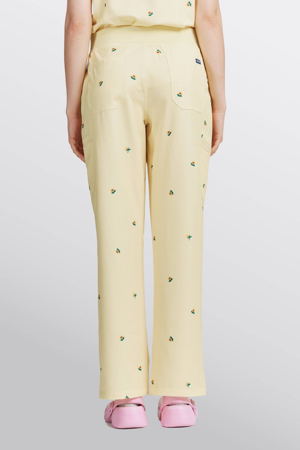 Back view of a veterinarian wearing light yellow scrub pants with sunflower print.