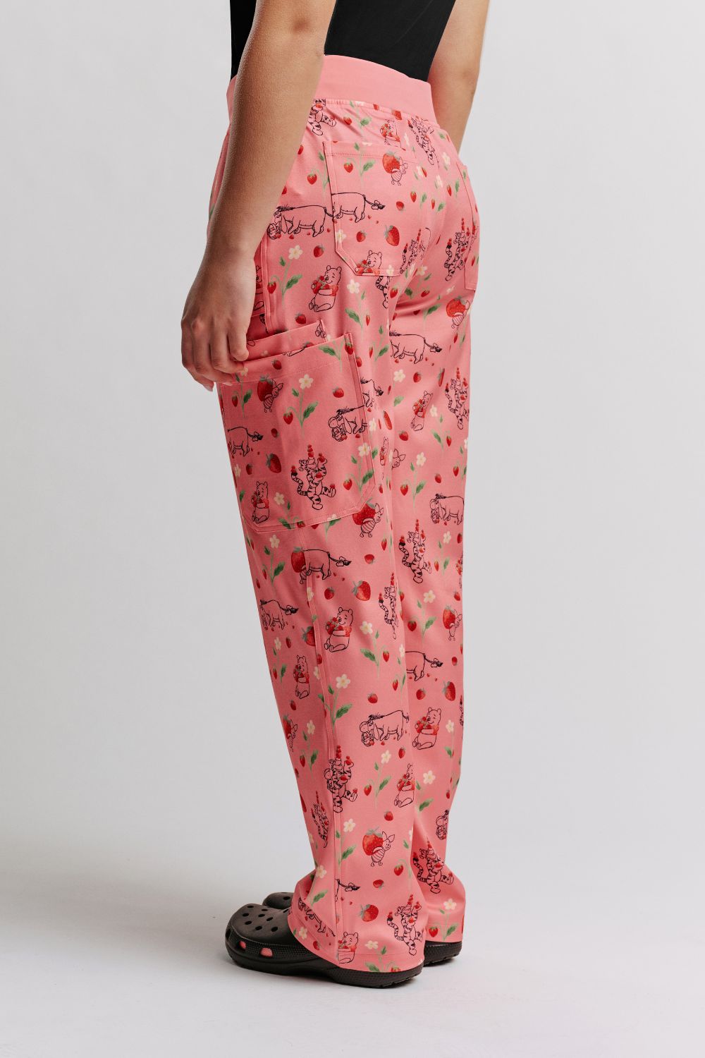 Back-quarter view of a veterinarian wearing light pink scrub pants with Winnie the Pooh strawberry print.