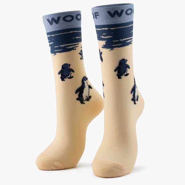 Pair of cream bamboo crew compression socks with penguin design standing against a plain white background.